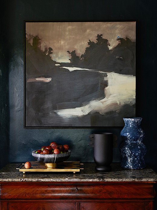 Forget the admonishment not to mix black and blue. Here the predominantly black artwork and the black vase make the deep blue wall seem lighter in comparison. Find the tray here and the bowl atop it here. Photo by Frank Francis.
